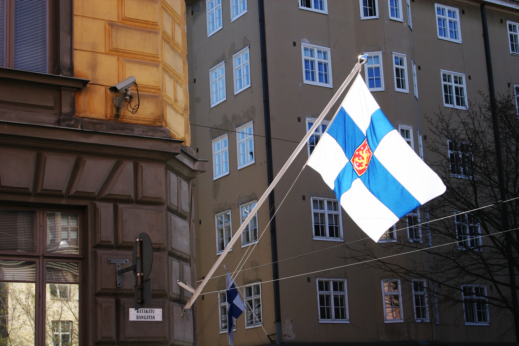 Kuvituskuva, Suojelupoliisin rakennuksen kulma osoitteessa Ratakatu 12 ja Suomen lippu. 